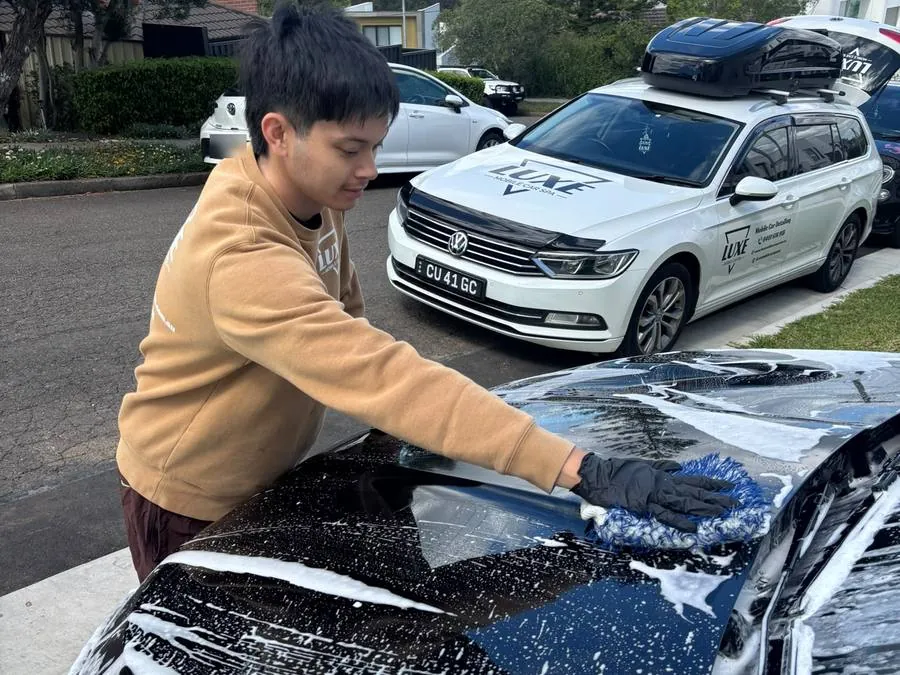 Tyrone hand washing a car at a customer's home